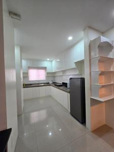 a kitchen with white cabinets and a black refrigerator at Sunny at DJE Villa in Angeles