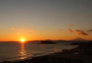 a sunset over the ocean with the sun in the sky at Kamakura Prince Hotel in Kamakura