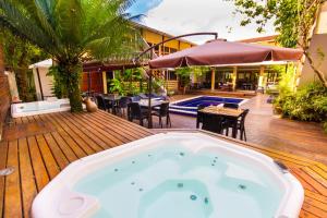 an outdoor hot tub on a wooden deck with a restaurant at Flat Vila Morena a pousada da sua família in Camburi