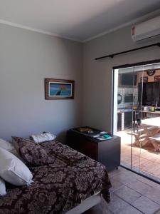 a bedroom with a bed and a sliding glass door at Pousada Muzeli in Itanhaém