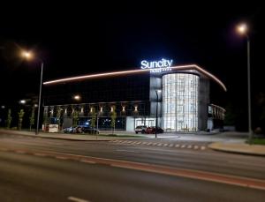a large building with a sign on it at night at Suncity Hotel & SPA in Šiauliai +63 photos