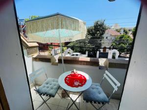 a table and chairs with a red umbrella on a balcony at Casa Torino in Santiago