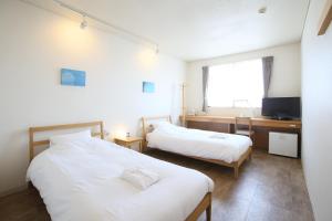 a bedroom with two beds and a desk and a television at Ishigakijima Hotel Cucule in Ishigaki Island