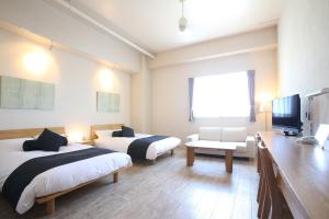 石垣島にある石垣島ホテルククルのベッド2台とテレビが備わるホテルルームです。
