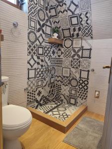 a bathroom with a toilet and a mosaic wall at Vikendica Monte Pino Romanija in Sokolac +32 photos