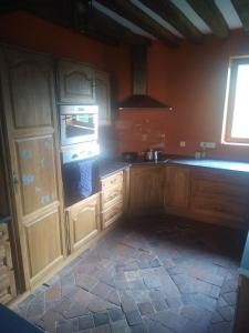 a kitchen with wooden cabinets and a stove top oven at Une maison traditionnelle à la campagne in Fruncé