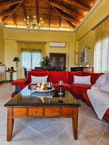 a living room with a red couch and a table at Villa Aitheras with sea views and garden in Stérnai +35 photos