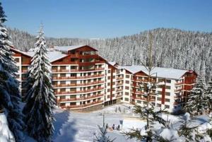 a large building in the middle of a snow covered forest at Апартаменти Форест Нук - ФАЗА 1 in Pamporovo