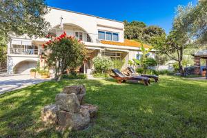 una casa con due panchine nel cortile di Apartments Blanka - Garden Oasis with Jacuzzi a Banjol