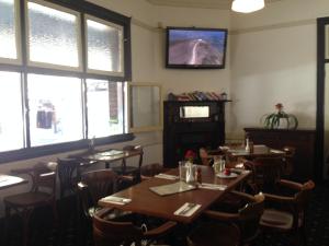 Mercantile Hotel في سيدني: غرفة طعام مع طاولات وكراسي ونوافذ