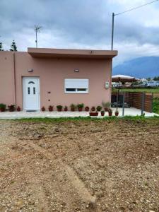 a small pink house with a white door at KaVros Cozy Apartment in Kavros