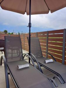a table and chairs under an umbrella on a deck at KaVros Cozy Apartment in Kavros +50 photos