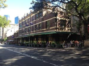 um prédio ao lado de uma rua com pessoas sentadas do lado de fora em Mercantile Hotel em Sydney