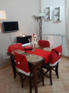 a dining room table with red chairs and a television at A casa di Miele in Campagnano di Roma