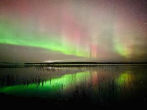 an aurora over a body of water at night at Lake Norva Lodge in Saarenkylä