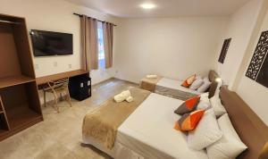 a hotel room with two beds and a flat screen tv at Pousada Noa in Cabo Frio