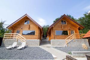 a log cabin with two white chairs in front of it at Long Rock Chalets in Rimetea +28 photos