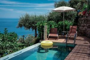 a swimming pool with two chairs and an umbrella at AMORE RENTALS - Villa Pittoresca in Ravello