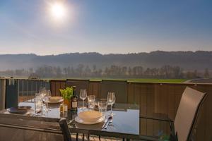 a table with wine glasses and plates on a balcony at TAMLiving Countryside 2BR Küche in Ottendorf bei Gleisdorf