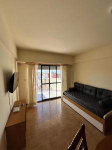 a living room with a black couch and a television at Departamento "La Casita" con Vista al Mar in San Clemente del Tuyú +3 photos
