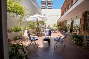 an outdoor patio with chairs and tables and an umbrella at Hotel Alhambra in Punta del Este