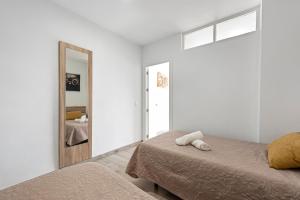 een witte slaapkamer met een bed en een spiegel bij Beach Palace Carihuela in Torremolinos +13 foto's