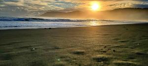 a beach with the sun setting on the ocean at Duon Baler - Seconds from Sabang beach, your peaceful escape in Baler