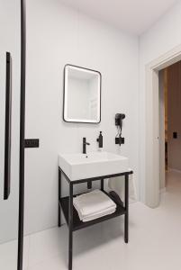 a white bathroom with a sink and a mirror at Apartament Husarski - City Park in Poznań