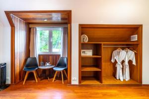 a room with a closet with two chairs and a table at Pousada Grandchamp - Campos do Jordao in Campos do Jordão +44 photos