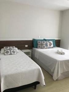 a bedroom with two beds with white sheets and blue pillows at Pousada Souza & Souza in Barra Velha
