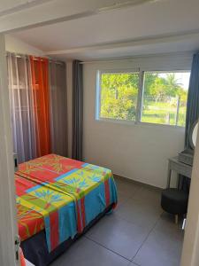 Un dormitorio con una cama y un escritorio y una ventana. en BAIE dES CARAIBES, en Baie-Mahault