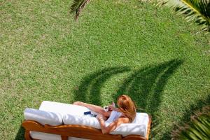 Eine Frau, die auf einer Couch im Gras sitzt. in der Unterkunft Mrs Chryssana Beach Hotel in Kolimvárion