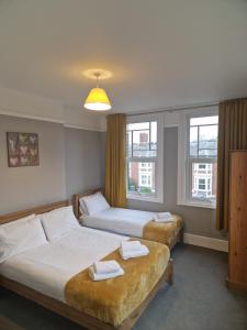 two beds in a room with two windows at Hereford - Falcon House - Spacious 5 Bedroom House With Games Room - Sleeps 14 Guests - Great Property For Family & Friends Gathering Together - Hosted by RENTMYHOUSE in Hereford