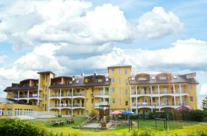 un edificio amarillo con un parque infantil delante de él en Aphrodite Hotel, en Zalakaros