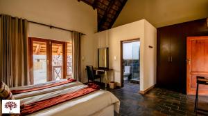 une chambre avec un lit, un bureau et une fenêtre dans l'établissement Zebula Golf and Wildlife Estate - Open Horizon Pax 8 - Moi Signature Luxury villa, à Mabula