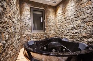 a bathroom with a black tub in a stone wall at One Luxury Suites in Belgrade