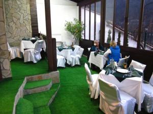 Zwei Personen sitzen an Tischen in einem Restaurant mit grünem Rasen in der Unterkunft Hotel Terazini in Weliko Tarnowo