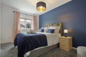 a blue bedroom with a bed and a window at St Abbs - Beautiful Home, EV, parking, garden in Hull