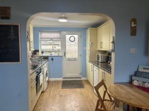 a kitchen with blue walls and a table and a door at Dunes View - Atlantic Bay in Perranporth