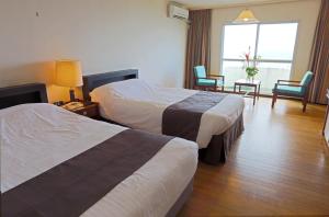 Lido Park Resort Hachijo في هاتشيجو: غرفة فندقية بسريرين ونافذة
