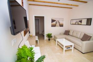 ein Wohnzimmer mit einem Sofa und einem Flachbild-TV in der Unterkunft Apartamentos Centro Puerto de Santa Maria in El Puerto de Santa María