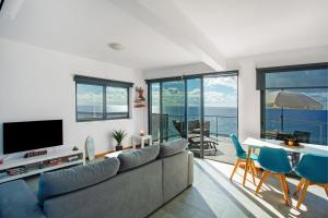 Una sala de estar con un sofá y una mesa con sillas. en The Wave House - Two Bedroom Flat, en Jardim do Mar