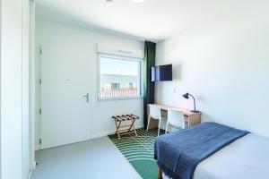a bedroom with a bed and a desk and a window at Student Factory Lyon Parilly in Vénissieux