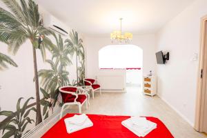 een kamer met een rode tafel en stoelen en een palmboom bij Apartament Faleza in Galaţi