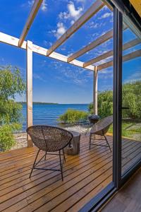 una terraza de madera con 2 sillas y una parrilla en OUTSCAPE l Cabañas Lago Puyehue, en Puyehue