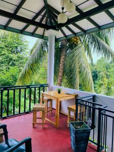 a porch with a wooden table and chairs and a palm tree at Stille Oase Inn in Matara