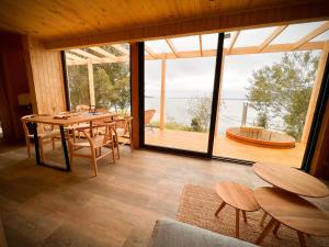 a room with a table and chairs and a large window at OUTSCAPE l Cabañas a Orilla del Lago Puyehue in Puyehue