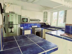 a kitchen with white cabinets and blue counter tops at Oasis Beach House in Sonsonate +6 photos