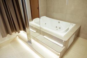 a bathroom with a white tub and a sink at Roma Hotel by H Hotéis - Airport in Brasília