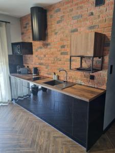 a kitchen with a sink and a brick wall at Apartament Garden in Leszno
